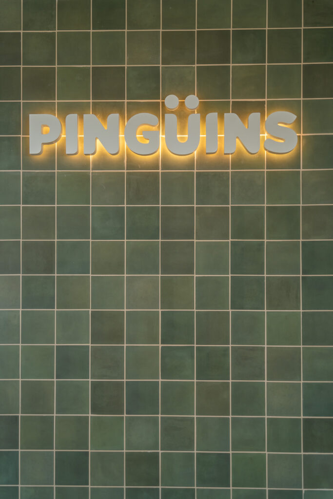Pared de azulejo verde con el logotipo de Pingüins iluminado