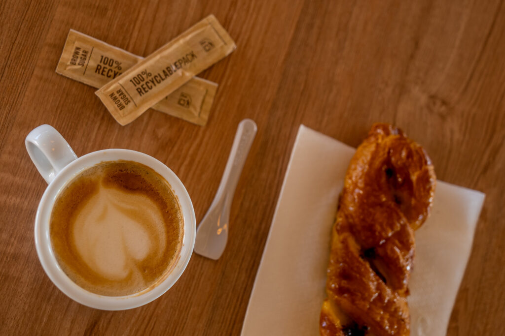 Desayuno de café con leche y porras sobre mesa de madera