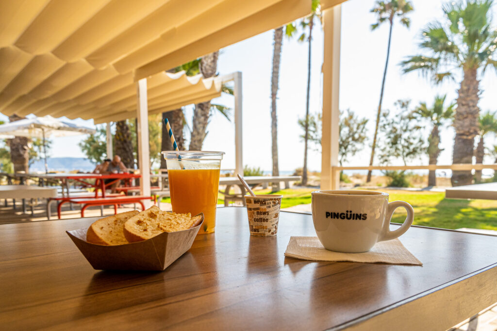 Mesa de la terraza con zumo de naranja, bollería y café frente a la playa