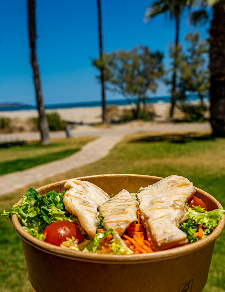 Ensalada de pollo a la plancha en bowl, con la playa al fondo