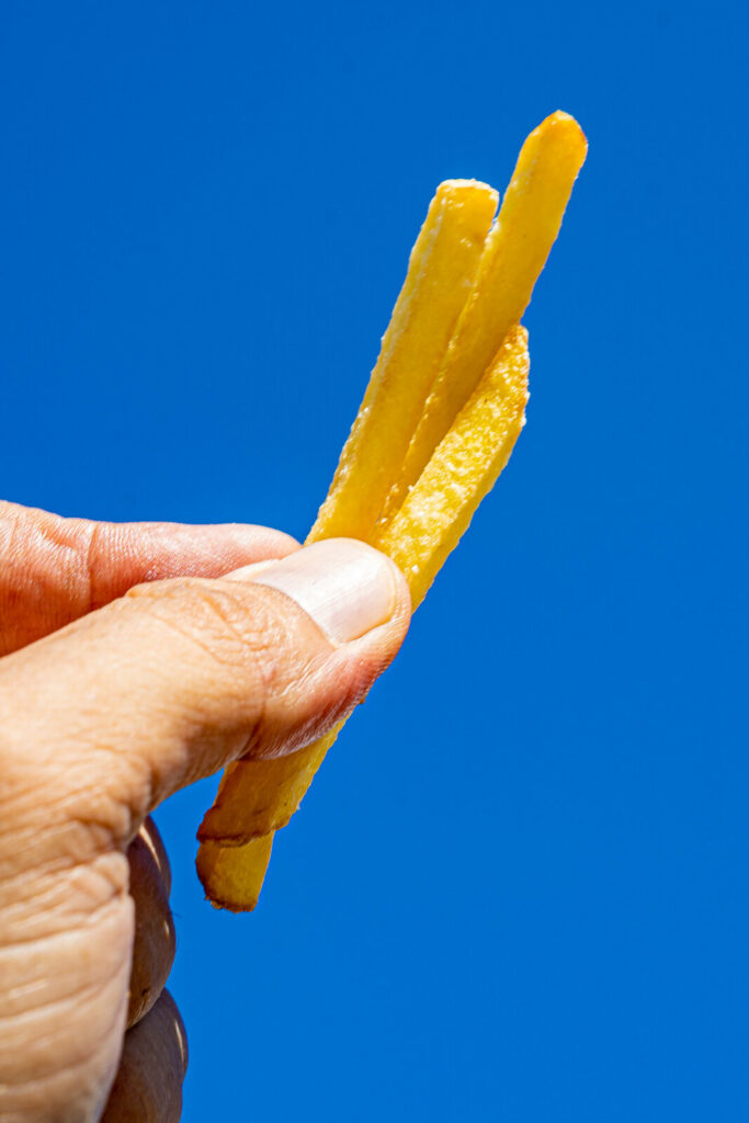 Patatas fritas sujetas contra el cielo azul